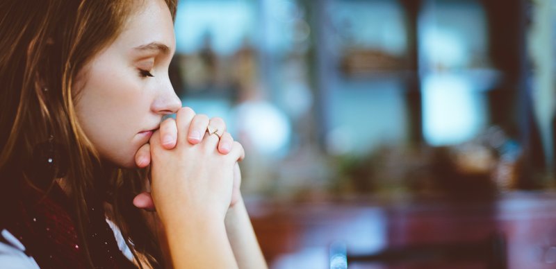 Side view of a beautiful woman praying with her eyes closed.